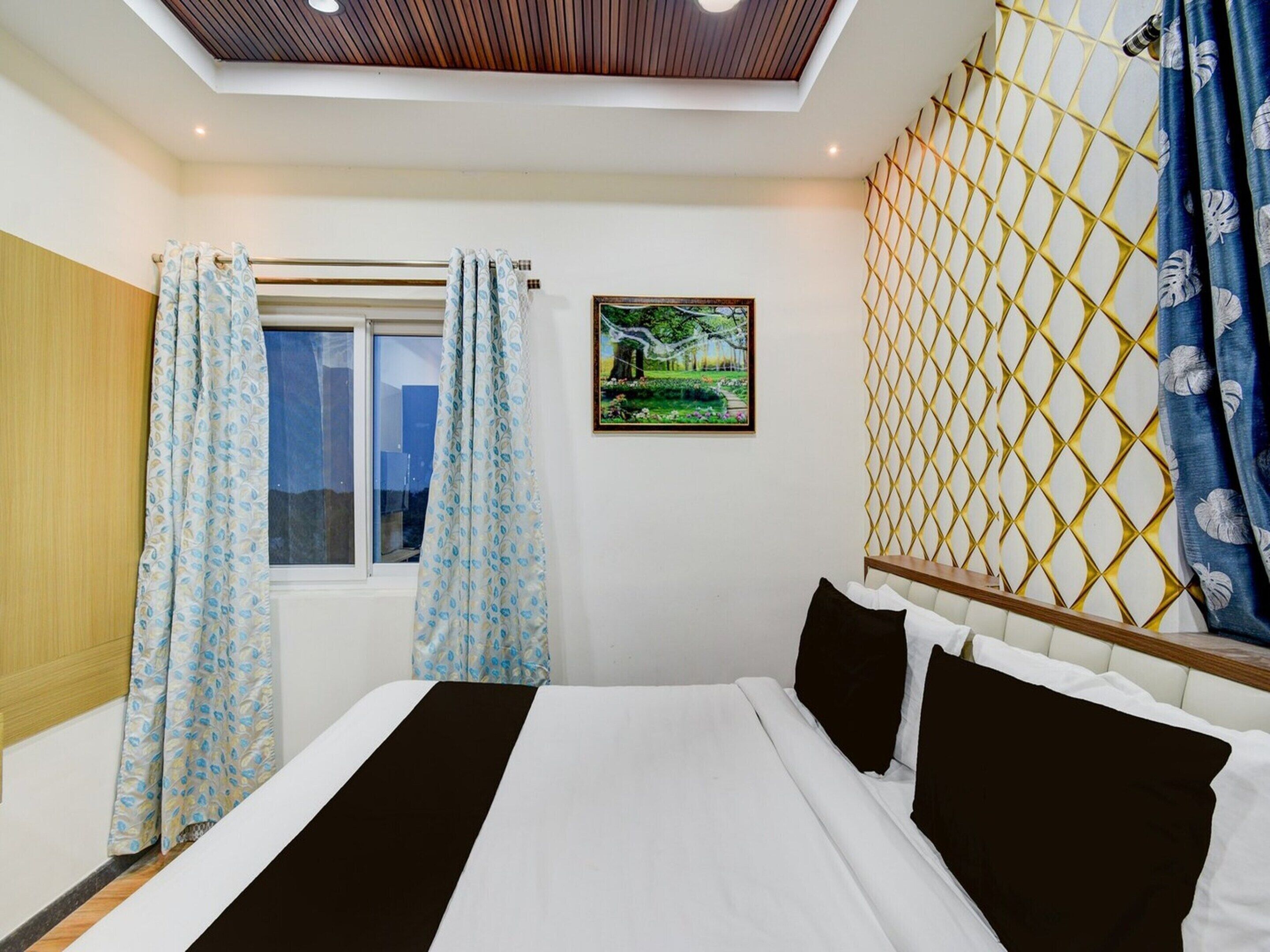 Een slaapkamer met een bed, gordijnen, een raam, een foto aan de muur en een plafondlamp.