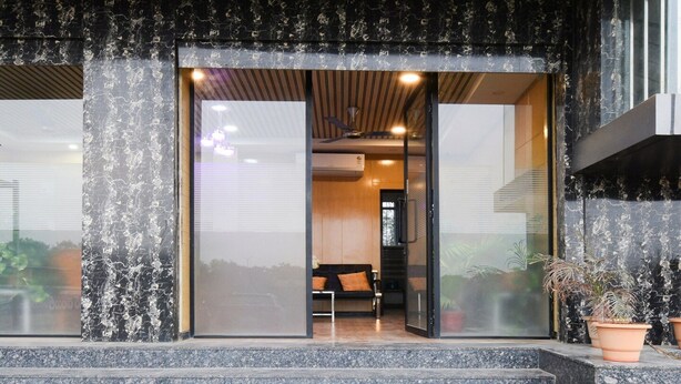 A building entrance with a glass door, steps leading up to it, and a seating area inside. - Deluxe Super Collection O Kollur Prime (Hyderabad)