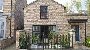 A brick building with a sign reading 'Eldon Terrace,' a gated entrance, and potted plants. - Eldon Terrace - Luxury 1 Bedroom Property (York)