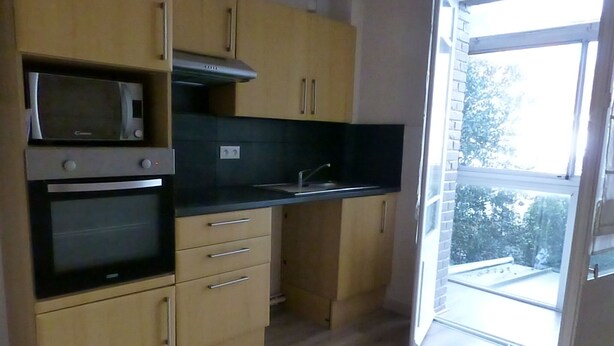 Eine Küche mit Holzausstattung, einer Mikrowelle, einem Backofen und einer schwarzen Arbeitsplatte.