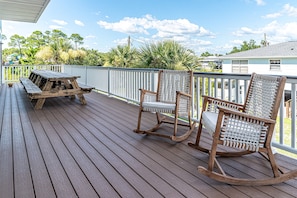 Eine Holzterrasse mit Picknicktisch und zwei Schaukelstühlen.