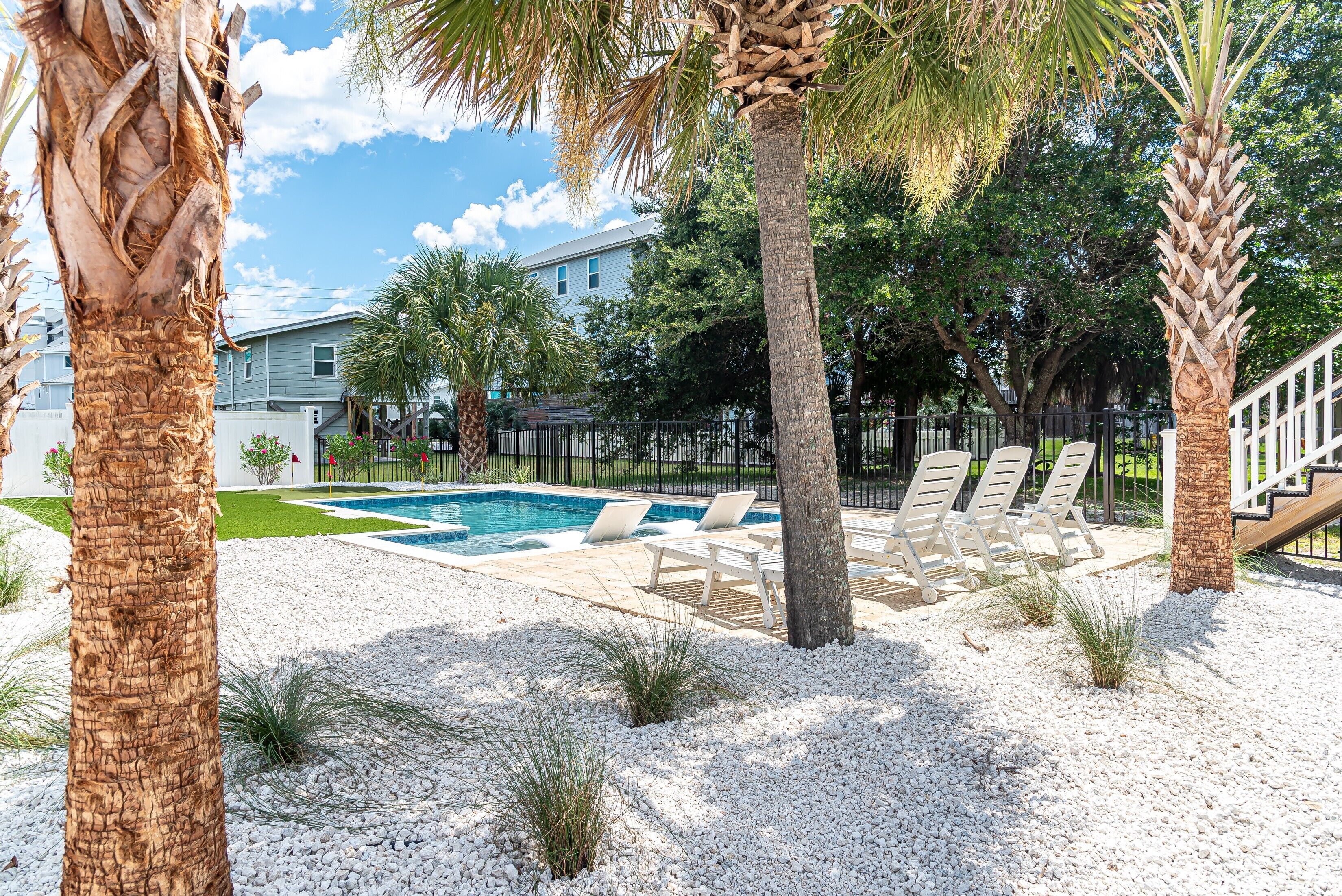 A swimming pool area with lounge chairs and palm trees.