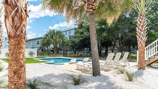 A swimming pool area with lounge chairs and palm trees. - Retreat in Gulf Shores| Luxury Pool• Tanning Shelf • Putting Green •Sleeps 14 (Gulf Shores)