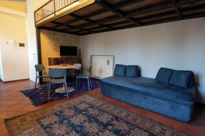 A living room with a sofa, chairs, a small table, and a TV.