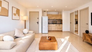 A modern living room with a sofa, a coffee table, and a kitchen in the background. - T2 Marina di Fiori - Mountain view for 2 people (Porto-Vecchio)