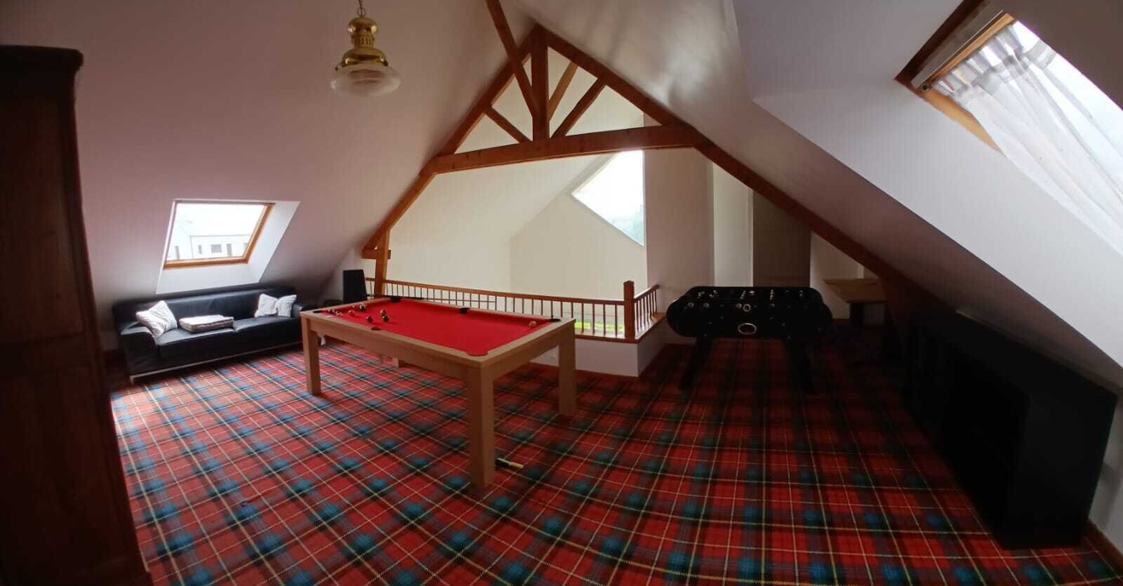 A room with a pool table, a sofa, a staircase, and a window.