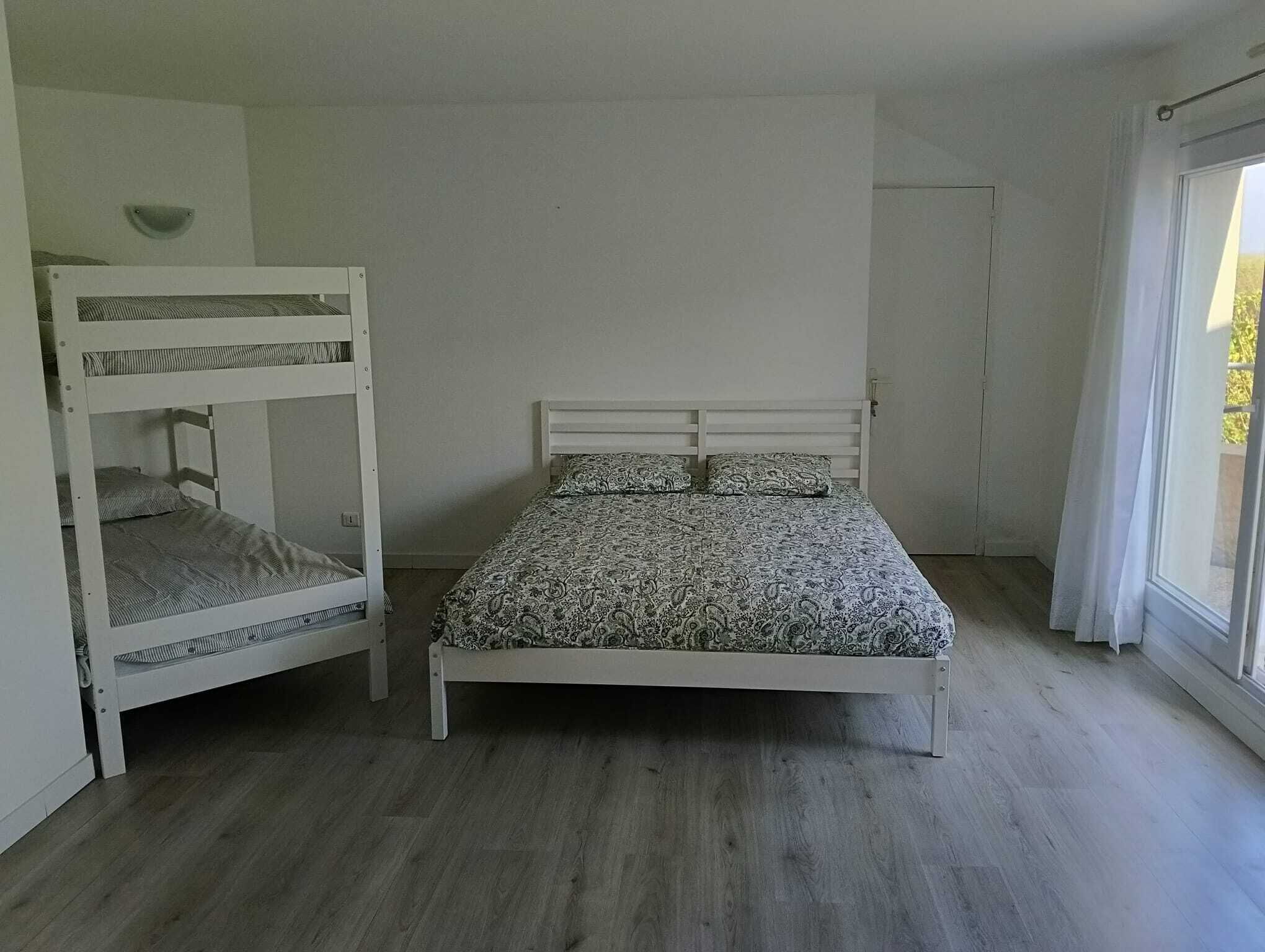 Una habitación con literas, una cama individual y una ventana con cortinas.