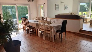 A dining area with a table and chairs, a sofa, and a view of the outdoors. - Ideal for groups: spa and leisure villas (Guégon)