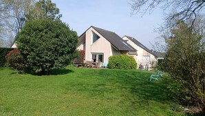A house with a sloped roof, a patio with outdoor furniture, and a well-maintained lawn. - Ideal for groups: spa and leisure villas (Guégon)