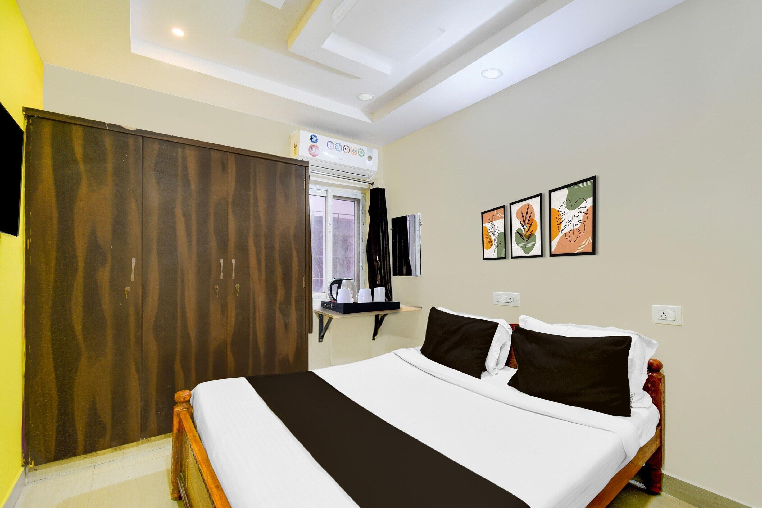 A hotel room with a bed, wardrobe, bedside table, and artwork on the wall.