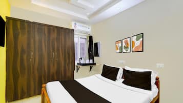 A hotel room with a bed, wardrobe, bedside table, and artwork on the wall.