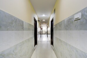 A hallway with marble walls and doors, leading to a bright room with a ceiling light. - Deluxesri Vinayaka Luxury Rooms (Hyderabad)