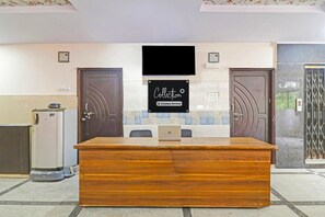A reception desk with a laptop, two doors, a tiled wall, and a sign that reads 'Collection Company-Serviced'. - Deluxesri Vinayaka Luxury Rooms (Hyderabad)