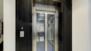 Een lift met een digitaal scherm, een glazen deur en een bedieningspaneel.