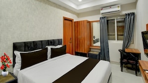 Een hotelkamer met een bed, een bureau, een stoel, een airconditioning en een kledingkast.