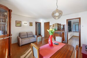 Een ruime woonkamer met een houten eettafel, een bank en een keuken op de achtergrond.