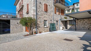 A stone building with multiple floors, balconies, and a gravel courtyard.