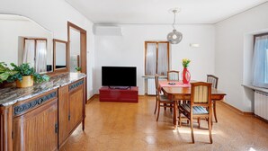 A living room with a TV, dining table, chairs, and a red cabinet.