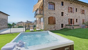A stone building with a hot tub, a lawn, and a clear sky.