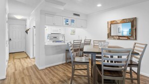 Une cuisine moderne avec des meubles blancs, une table à manger avec des chaises et un grand miroir au mur.