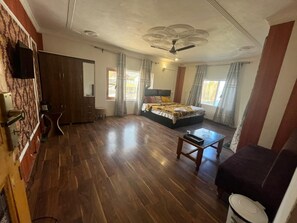 A bedroom with a bed, a desk, a chair, a wardrobe, and a bathroom. - Gulmarg Gateway Srinagar Tangmarg Rd (Baramula)