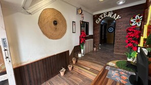 Zona de recepción con un banco de madera, un reloj en la pared, un letrero que indica 'ABRIR' y un cartel que dice 'GATEWAY' sobre un arco.