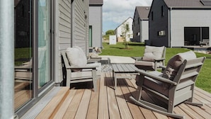 Une terrasse dotée de mobilier d’extérieur, d’une porte vitrée et offrant une vue sur les maisons voisines.