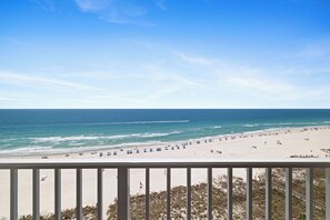 A beach view from a balcony with a railing, ocean, and beach umbrellas. - Bluewater 1205 by Liquid Life (Orange Beach)