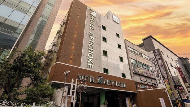 Un edificio a più piani con un cartello ben visibile che recita 'HOTEL ARTICHOKE'.