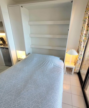 Ein Schlafzimmer mit Bett, Schreibtisch und Lampe.