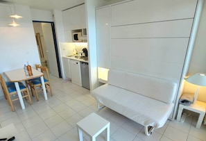 Ein kompakter Wohnbereich mit Küchenzeile, einem Essbereich mit Tisch und Stühlen sowie einer Couch.