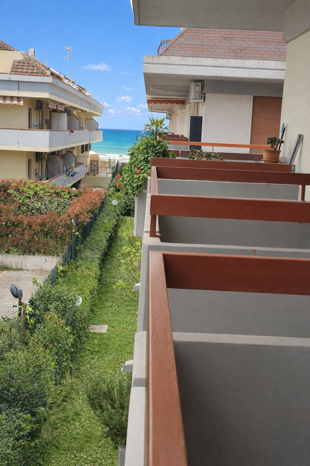 Ein Wohngebäude mit einem Balkon mit Blick auf einen Strand.