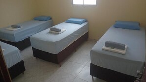 Una habitación con cuatro camas individuales, cada una con colchón y almohada azules, dispuestas en fila.