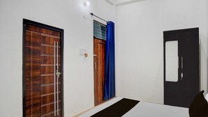 Um corredor com três portas, uma com detalhe em painel de madeira, outra com cortina azul e uma terceira com porta preta.