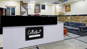 A reception desk with a sign reading 'Collection Company-Serviced' and a blue sofa in the background. - Deluxe sri Balaji Luxary Rooms (Hyderabad)