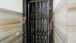A modern elevator with a black metal gate and marble walls. - Deluxe sri Balaji Luxary Rooms (Hyderabad)
