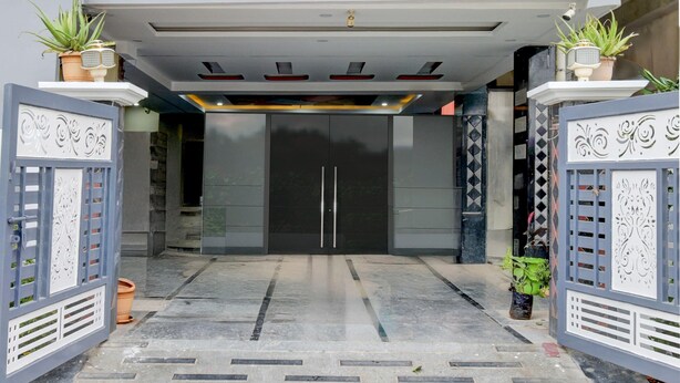 A building entrance with a double door, decorative gates, and potted plants. - Deluxe sri Balaji Luxary Rooms (Hyderabad)