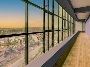 A long corridor with large windows offering a view of a cityscape. - Super Townhouse Madgaon (Margao)