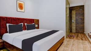 Habitación de hotel con una cama grande, cabecera roja, una obra de arte enmarcada y suelo de madera.