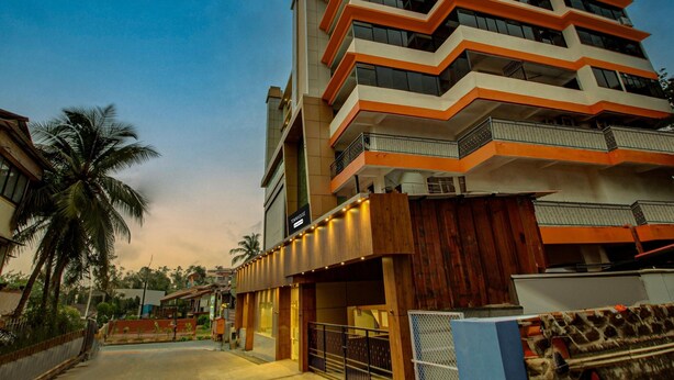 Un hotel de varios pisos con un diseño arquitectónico moderno, con balcones y una entrada destacada.