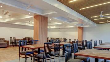 A spacious indoor area with multiple tables and chairs, ceiling fans, and recessed lighting.