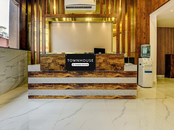 Un comptoir d’accueil avec un plateau en marbre, une enseigne indiquant « TOWNHOUSE, services d’entreprise », et un distributeur d’eau.