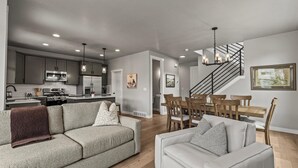 Eine moderne Küche mit Edelstahlgeräten, eine Essecke mit Holzkästen und eine Treppe, die zu einer weiteren Ebene führt.
