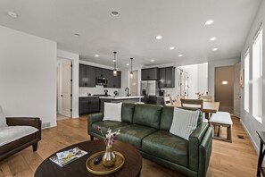 Ein modernes Wohnzimmer mit einem grünen Sofa, einem Couchtisch mit Zeitschriften und einer Vase mit Blumen.