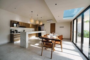 Een moderne keuken met een marmeren eiland, houten kastjes en hangende lampen.