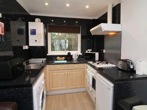 A modern kitchen with a black countertop, wooden cabinets, a window, and a built-in stove.