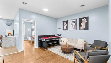 A modern living room with a pool table, a sofa, and a coffee table.