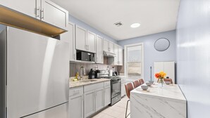 Una cucina moderna con frigorifero, fornello, microonde e zona pranzo con sedie e tavolo.