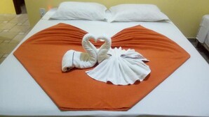 En säng med ett orangefärgat överkast och två vita handdukar som är arrangerade i form av en svan.