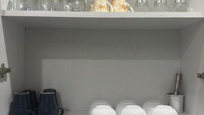 A white shelf with clear glass jars, ceramic mugs, and a metal coffee grinder. - The golden nest (Hyderabad)